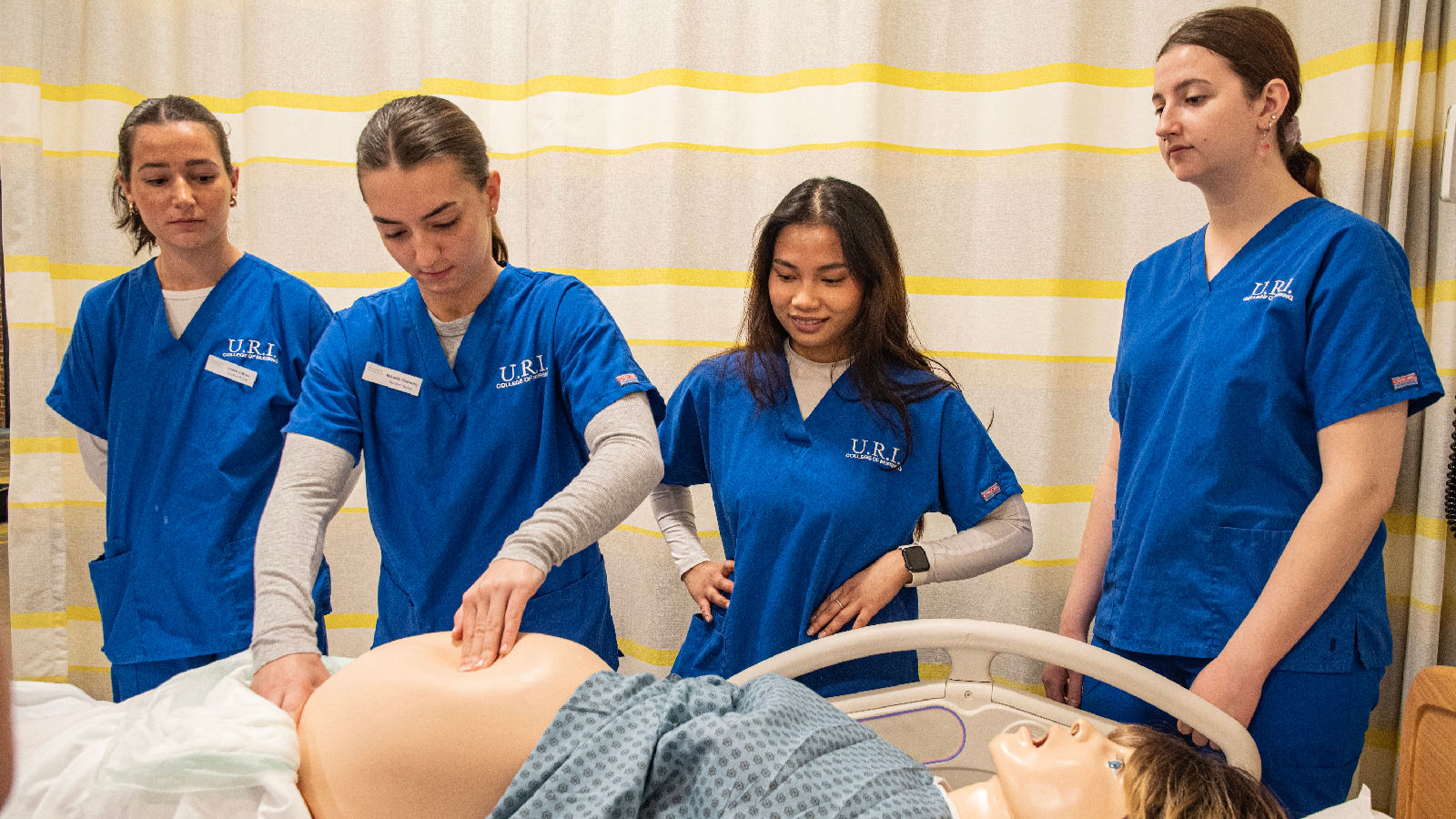 Four nursing students with a life-size robotic patient.